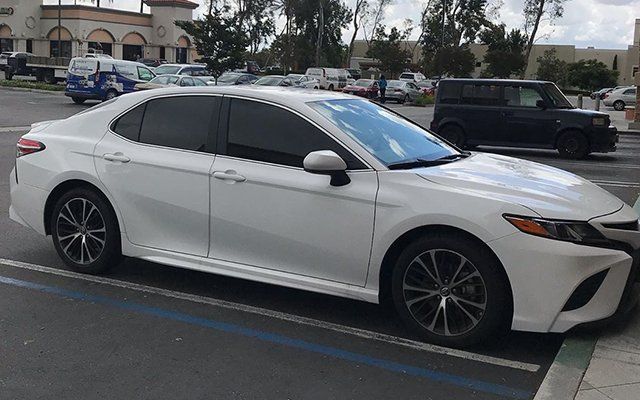 A white toyota camry is parked in a parking lot.