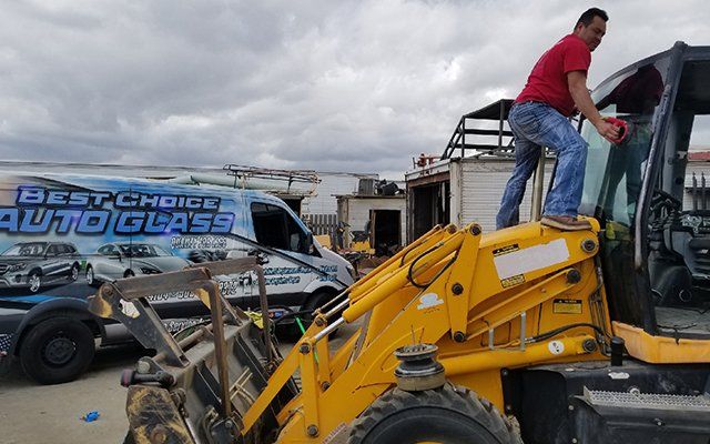 A man is standing on top of a yellow tractor.