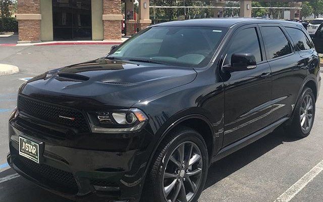 A black dodge durango is parked in a parking lot.
