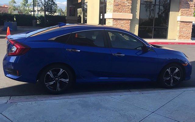 A blue honda civic is parked in front of a building.