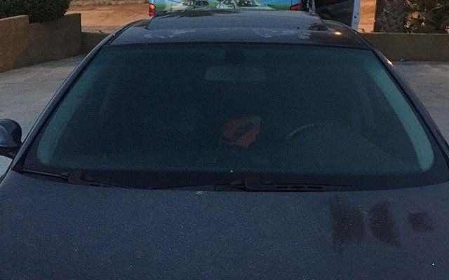 A man is sitting in the driver 's seat of a black car.