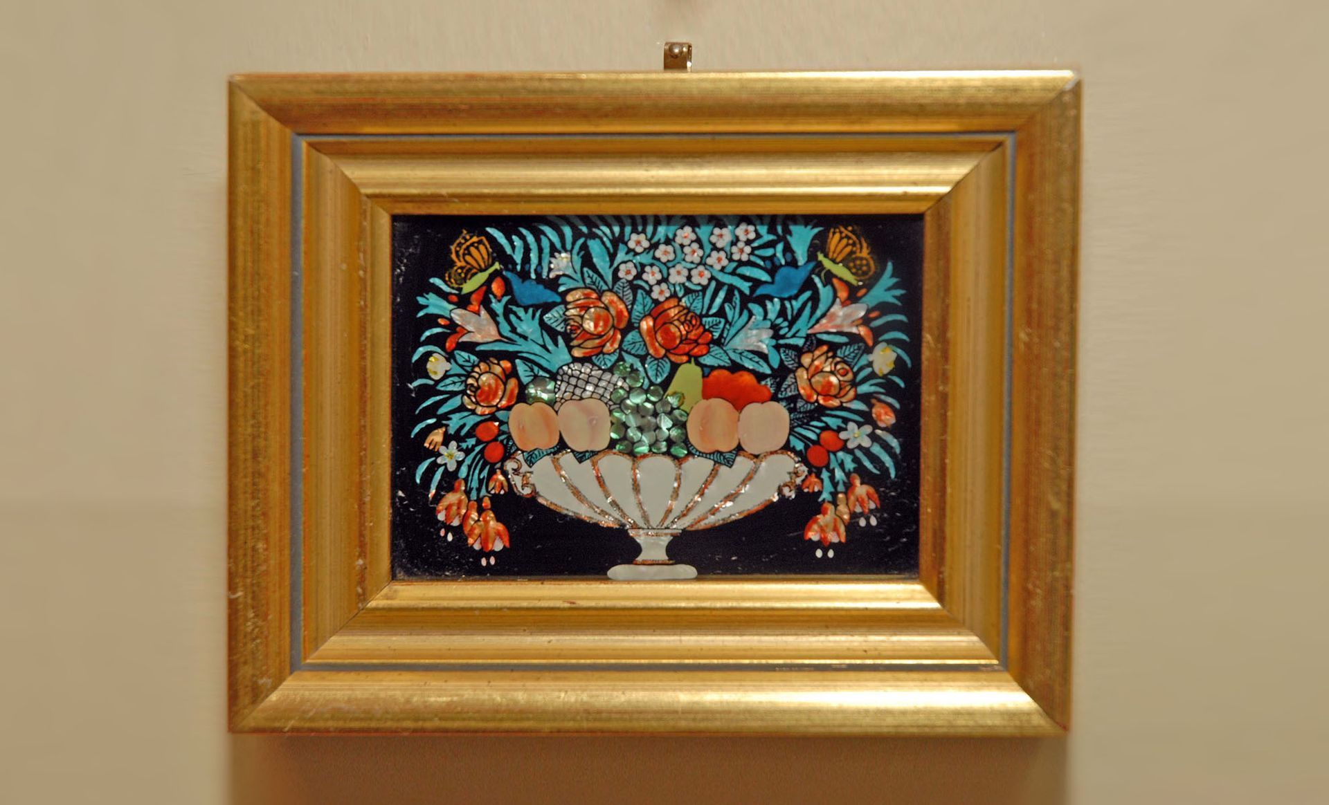A picture of flowers in a vase in a gold frame