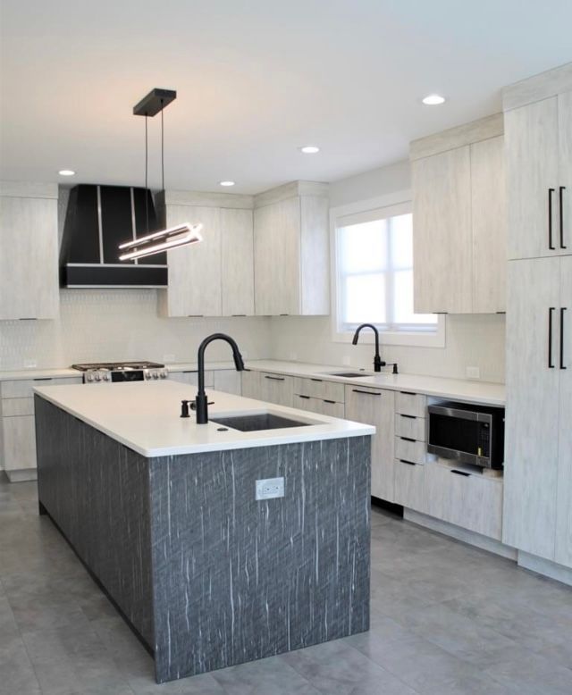 A kitchen with white cabinets and a large island in the middle