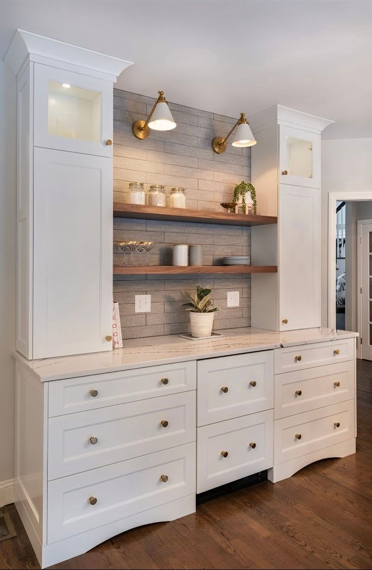A kitchen with white cabinets , drawers , and shelves.