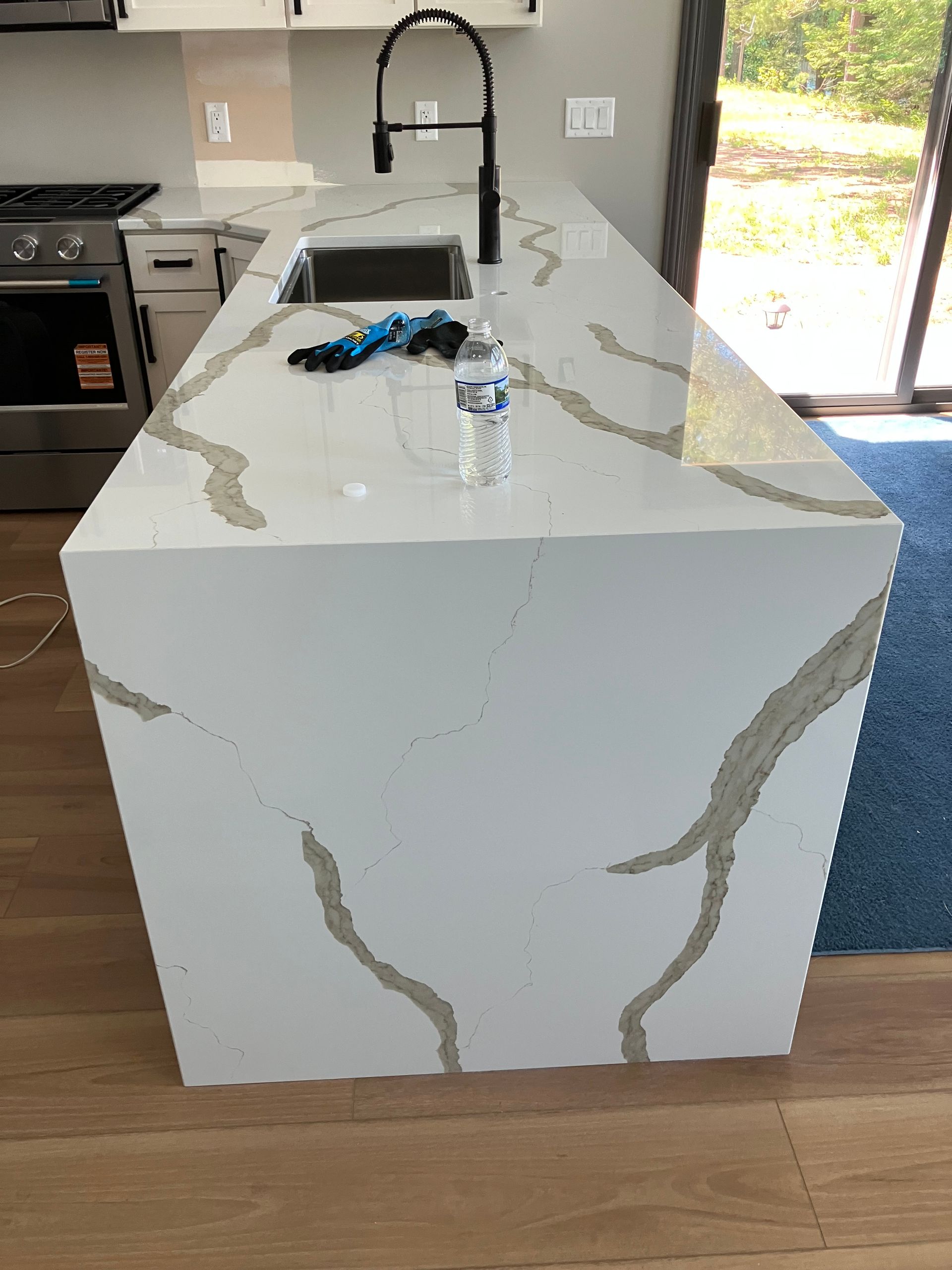 White marble kitchen island with black faucet, keys, and a water bottle on top