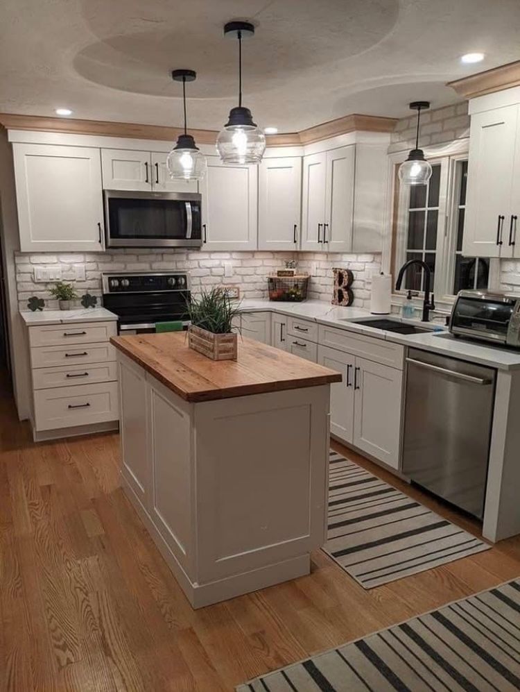 A kitchen with white cabinets, stainless steel appliances, and a large island.