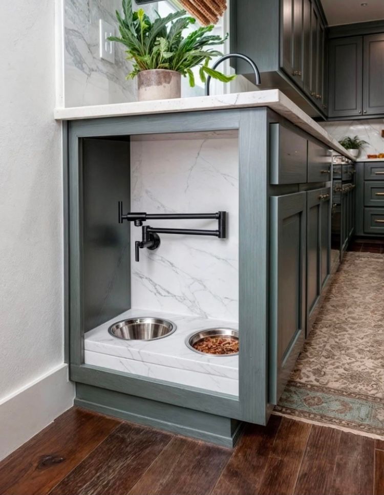 A kitchen with a sink and two dog bowls underneath it.