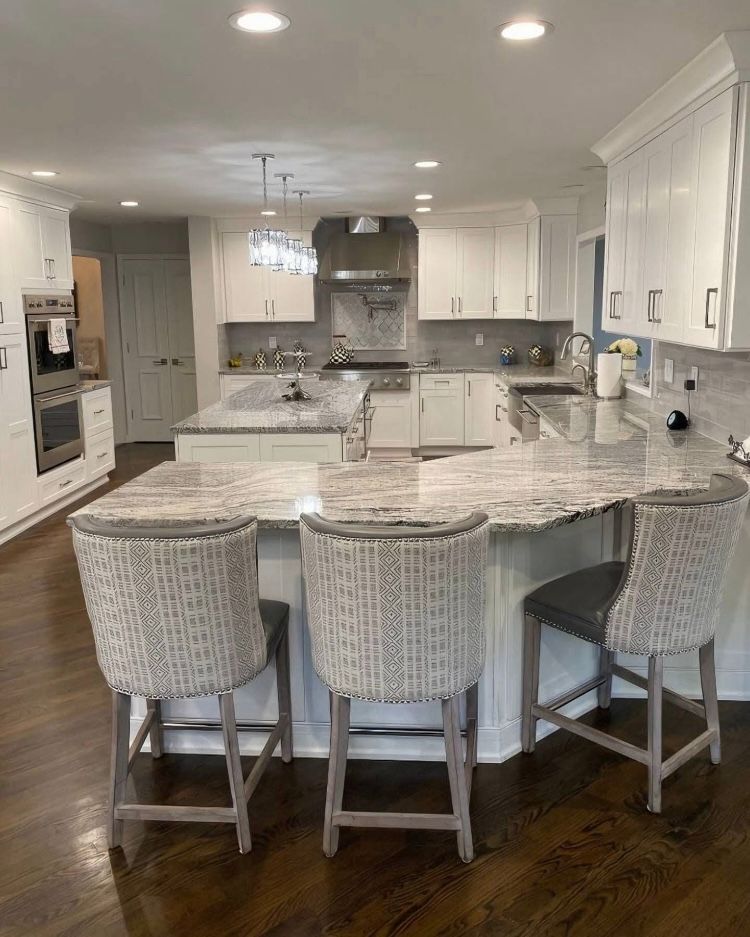 A kitchen with a large island and wicker chairs.