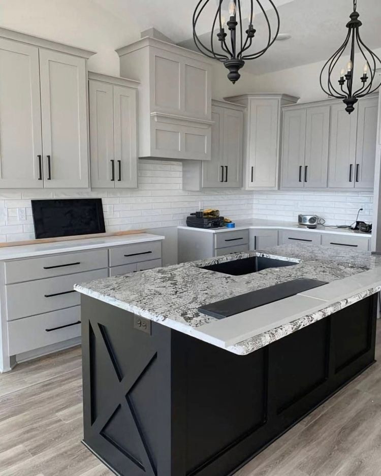 A kitchen with white cabinets and a black island with a sink.