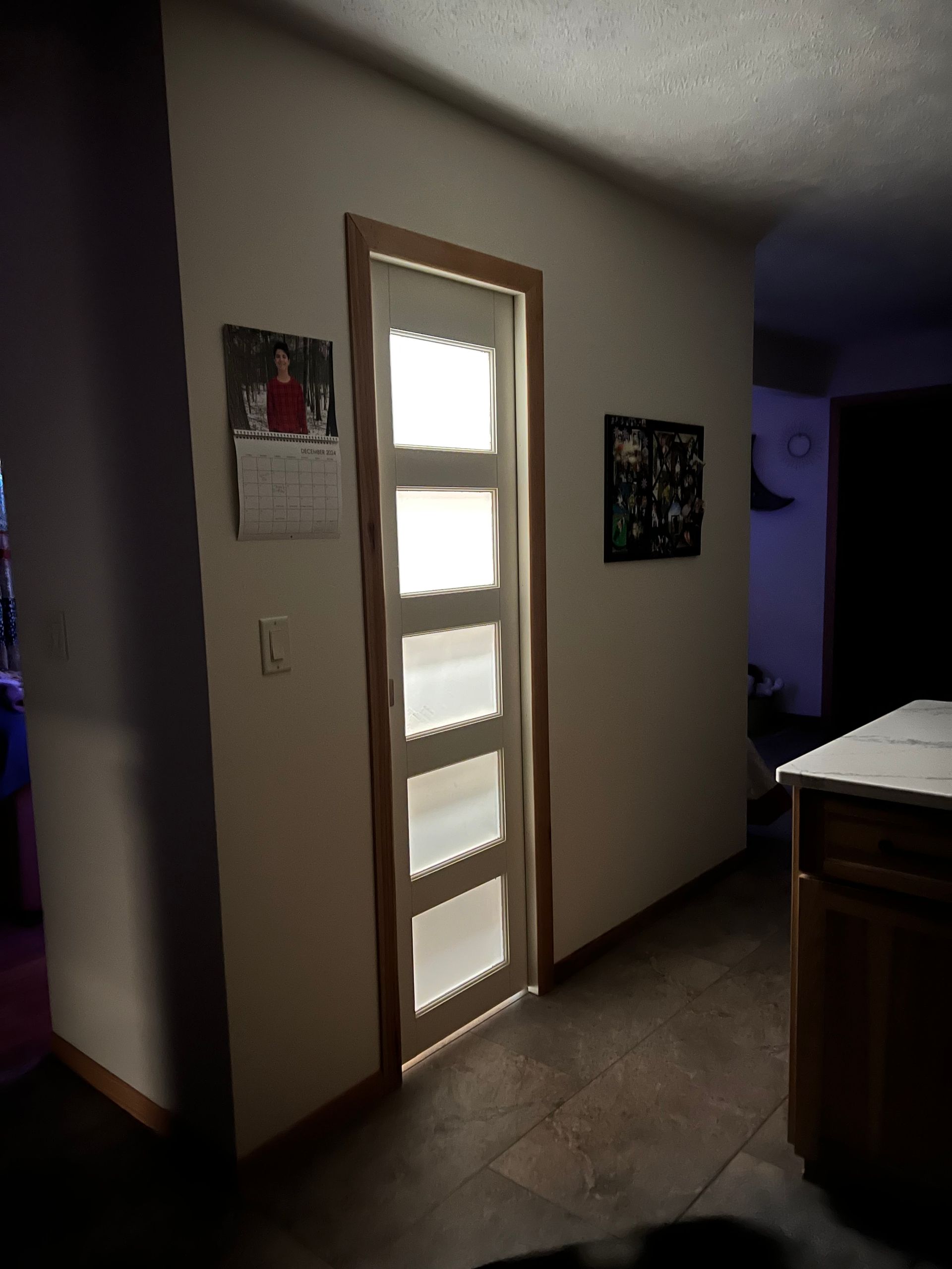 A hallway with a door and a calendar on the wall.