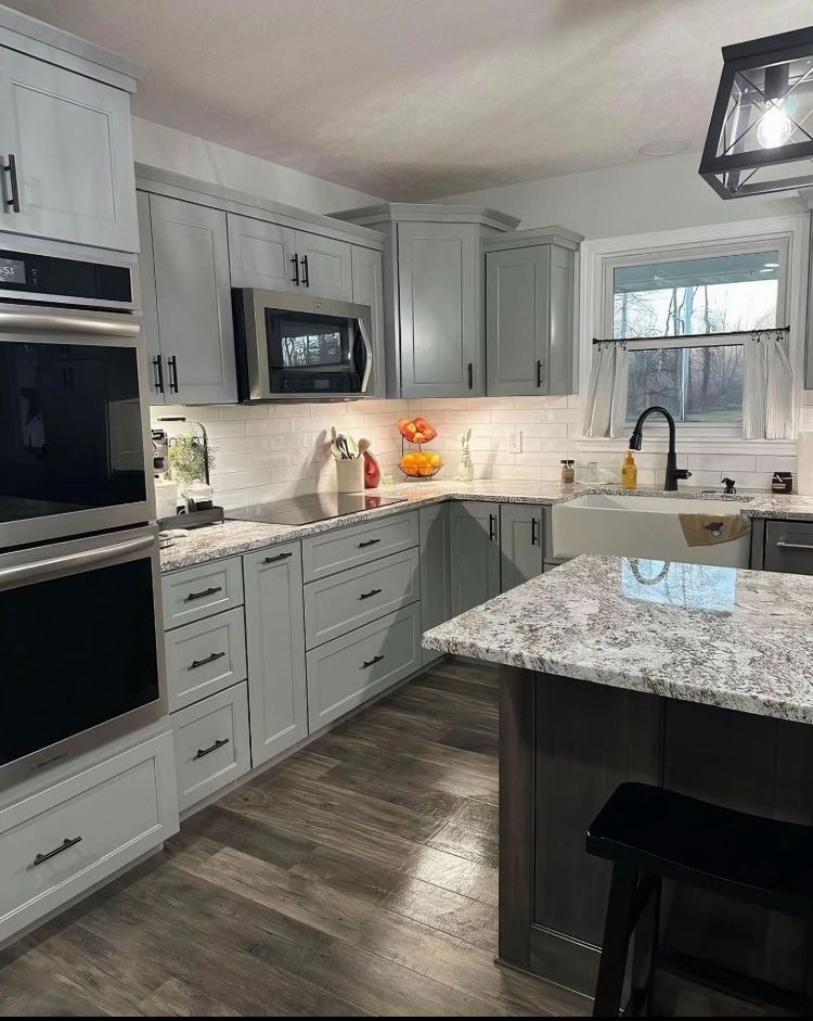 A kitchen with white cabinets, granite counter tops, stainless steel appliances, and a sink.