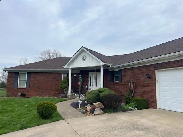A brick house with a white porch and a white garage door.