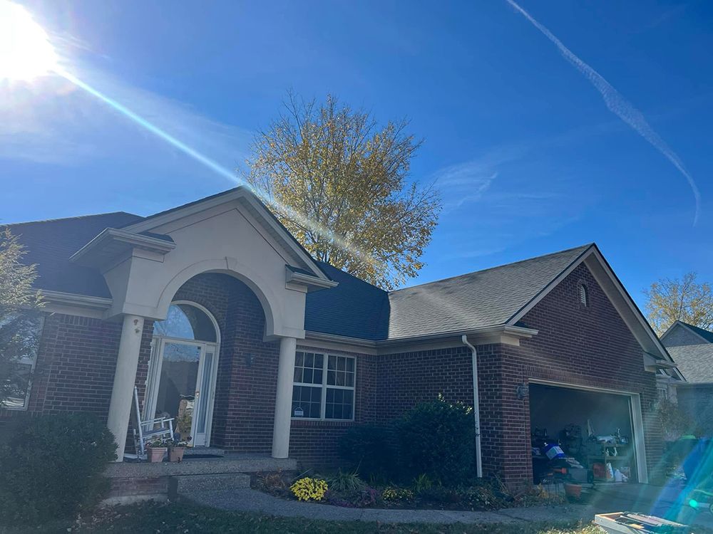 A brick house with a black roof and a blue sky in the background.