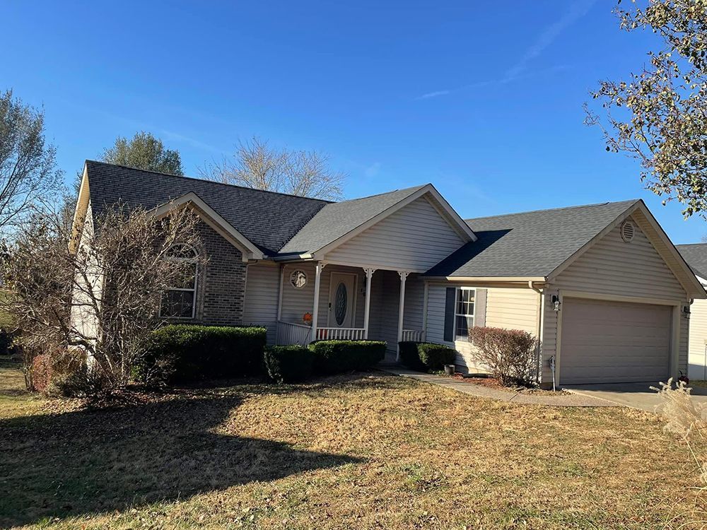 A white house with a gray roof and a large porch.