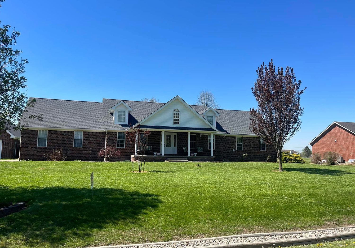 A large brick house with a large lawn in front of it.