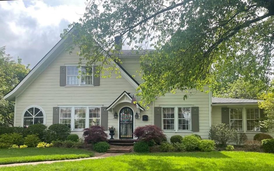 A large white house with a lush green lawn in front of it.
