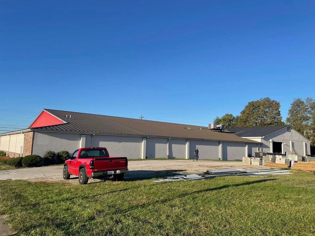 A red truck is parked in front of a large building.