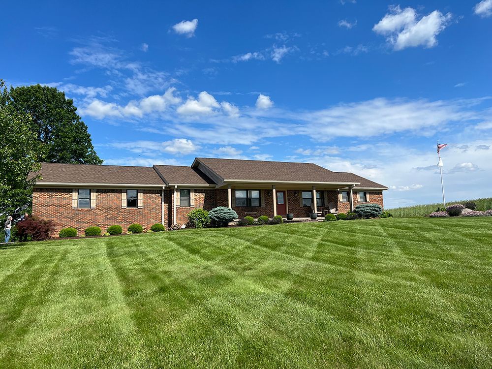 A brick house with a large lush green lawn in front of it.