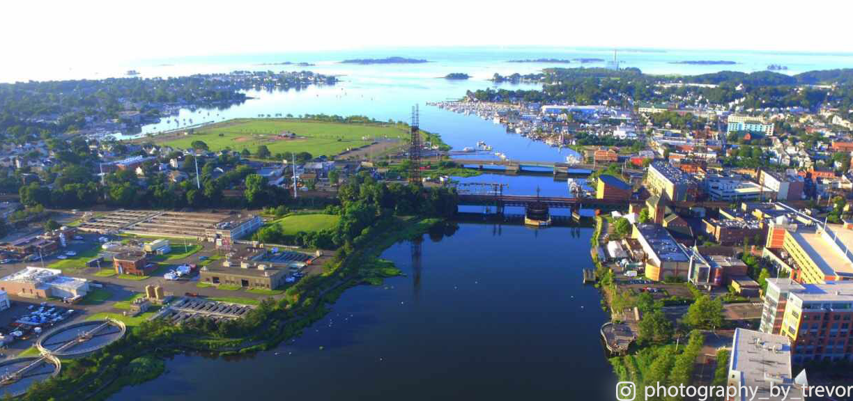 Aerial view of a river bridge connecting a green waterfront town at sunset