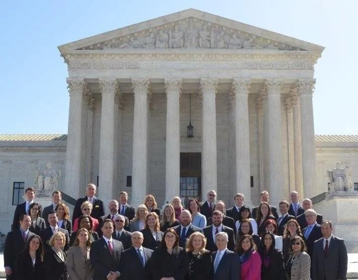 Group of people posing on the steps of the U.S. Supreme Court building