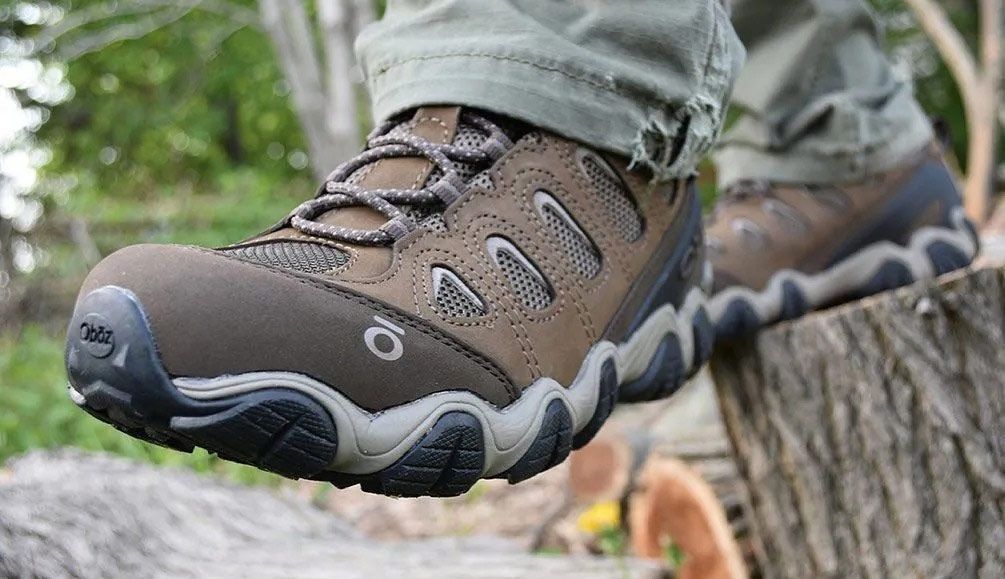 Person wearing dark blue hiking boots in a forest setting.