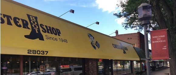 Exterior of Foster Boot Shop with yellow awning, blue sky, and Welcome to Statesville banner.