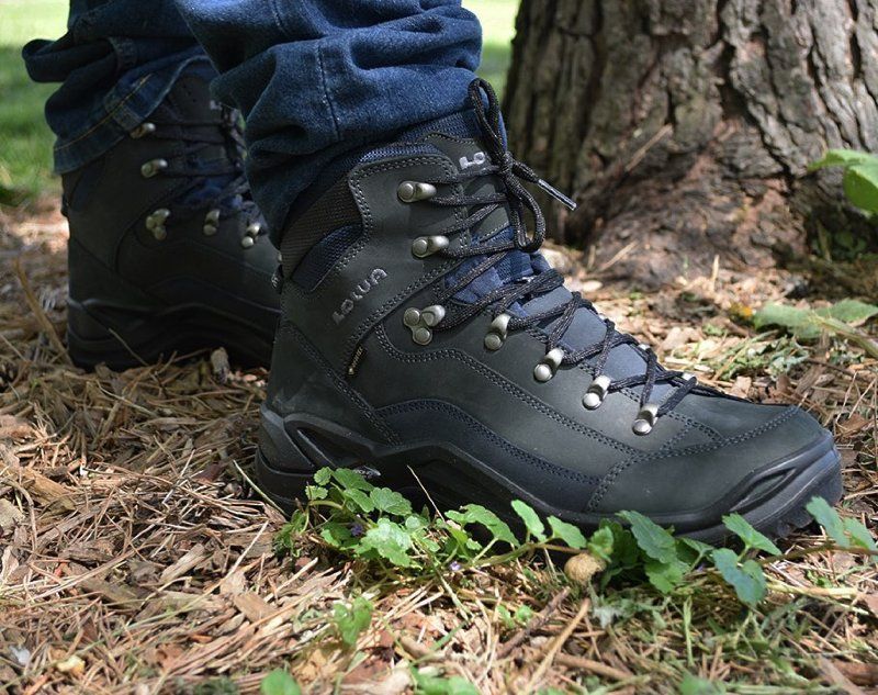 Person wearing dark blue hiking boots in a forest setting.
