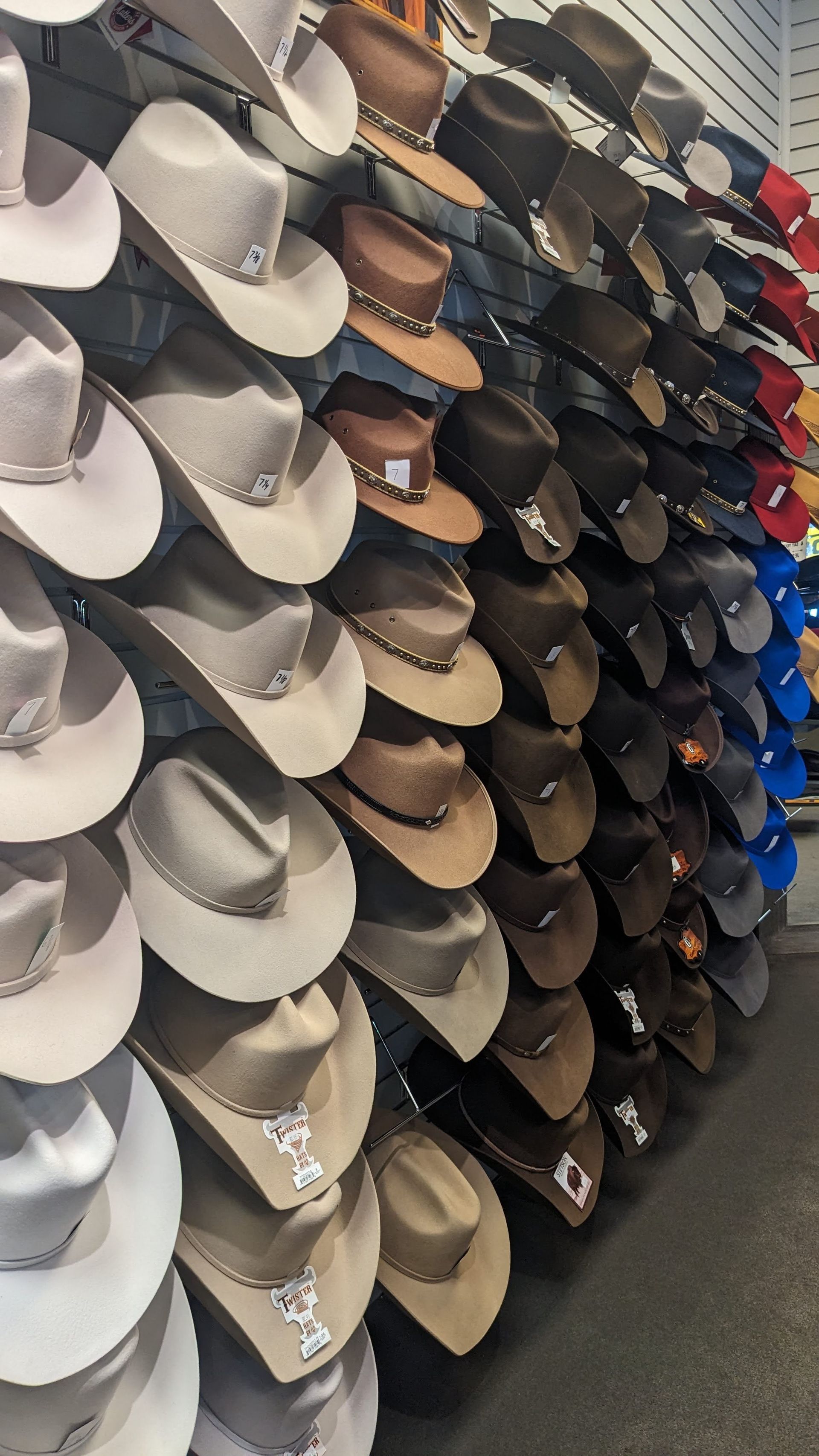 Wall of cowboy hats in various colors, styles, and decorations.