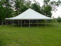 A large white tent is sitting in the middle of a grassy field.