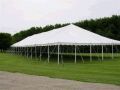 A large white tent is sitting in the middle of a grassy field.