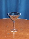 A martini glass is sitting on a wooden table.
