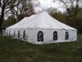 A large white tent is sitting in the middle of a grassy field.