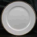 A white plate with a gold rim is sitting on a table.