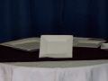 A table with plates and napkins on it in front of a blue curtain.