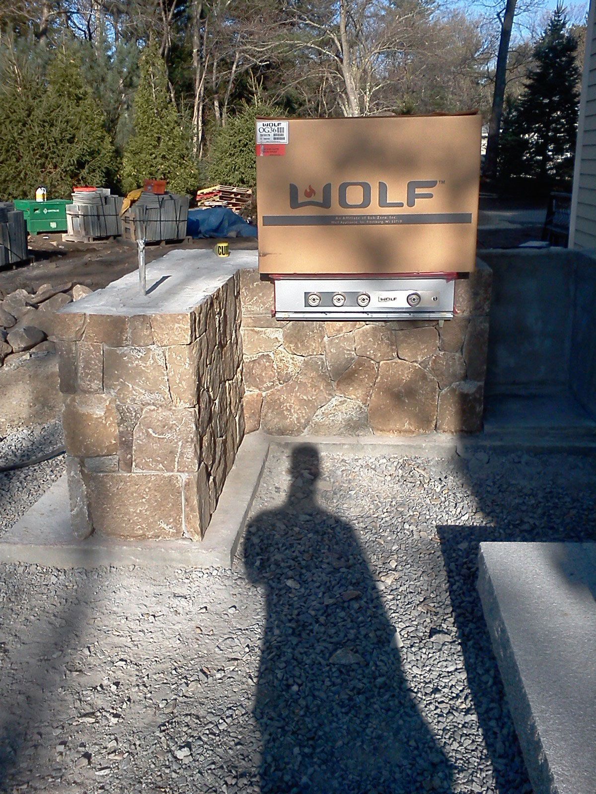 Concrete sign reading “WOLF” at an outdoor entrance, with stone walls and gravel path.