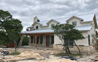A large white house with a metal roof is being built.