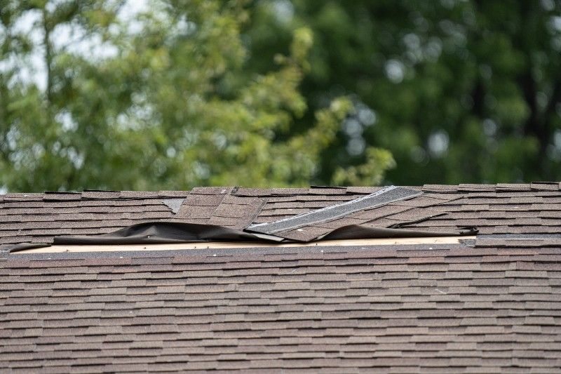 A roof with a hole in it and trees in the background.