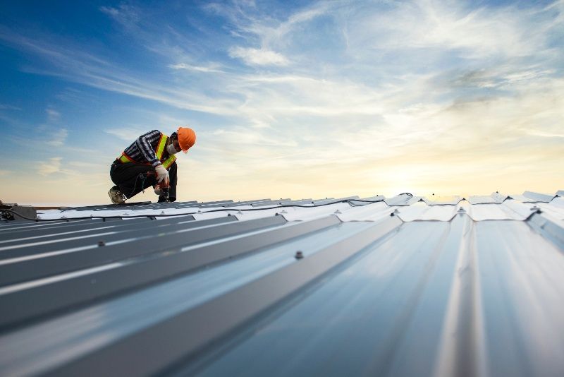 A construction worker is working on a metal roof.