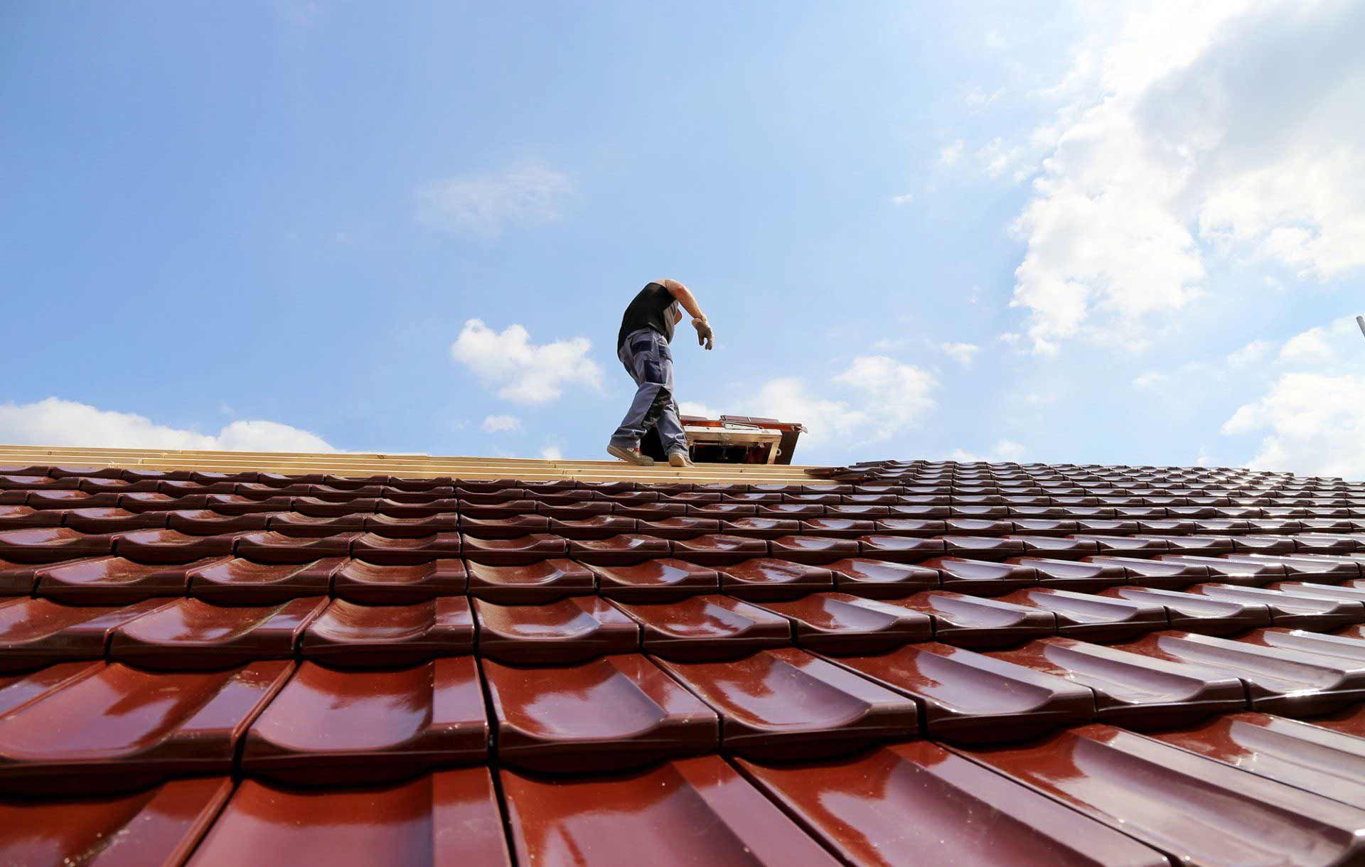A man is standing on top of a tiled roof.