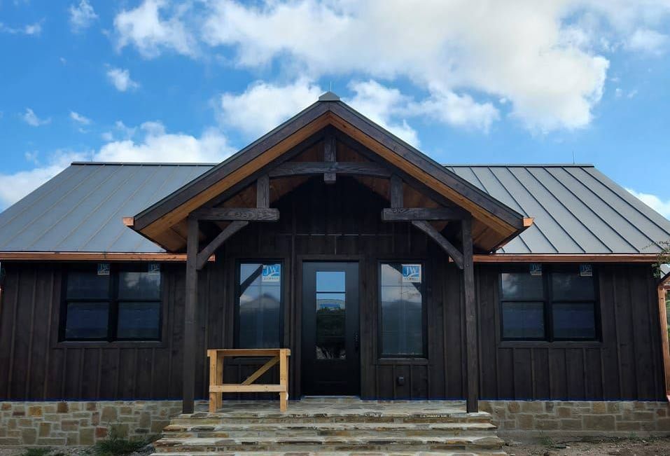 The front of a house with a metal roof and a wooden porch.