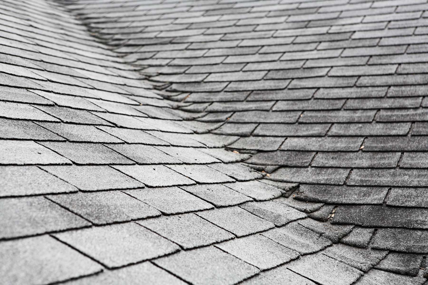 A black and white photo of a roof with a broken shingle.