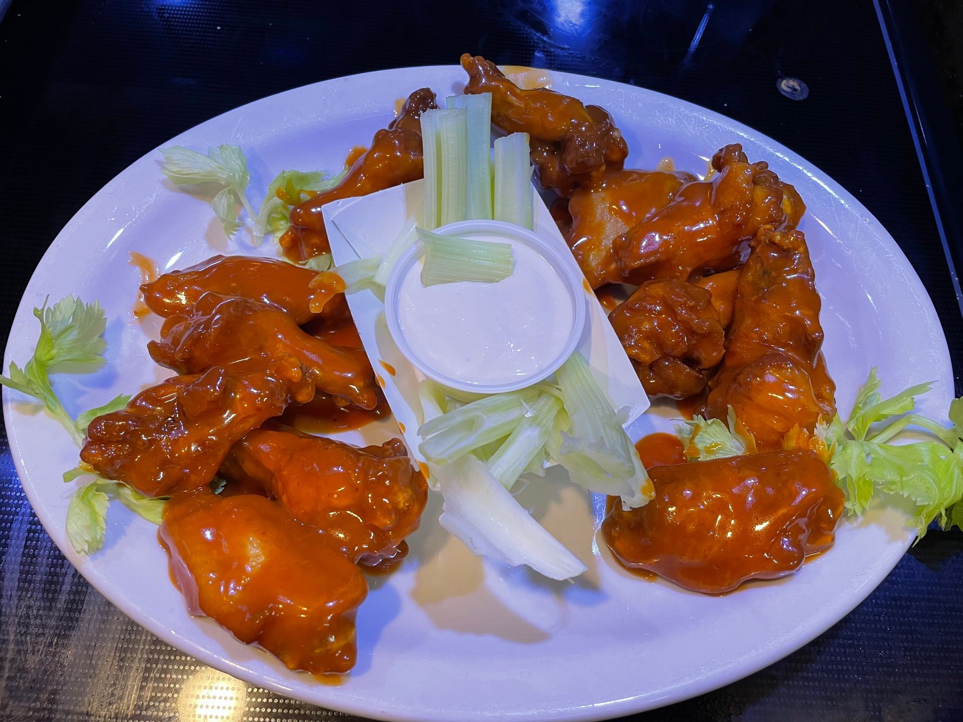 A white plate topped with chicken wings, celery, and dressing