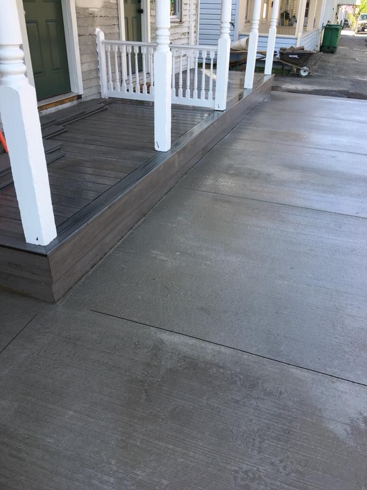 a concrete porch with a white railing next to a house