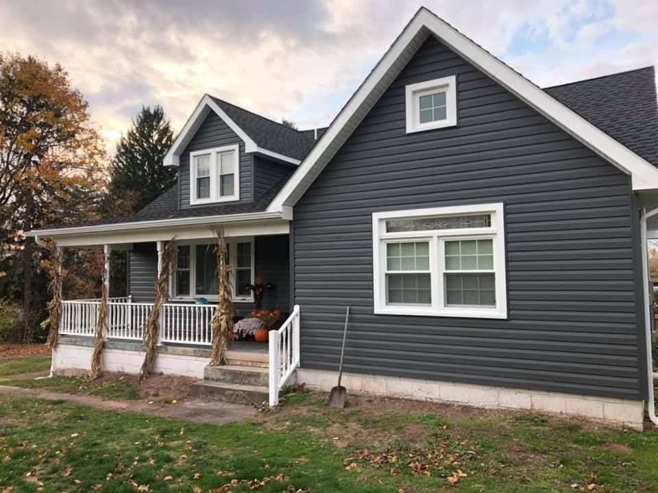 a gray house with a white porch and a shovel in front of it