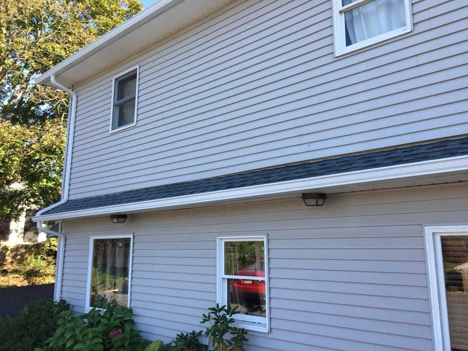 the side of a house with a gray siding and a black roof