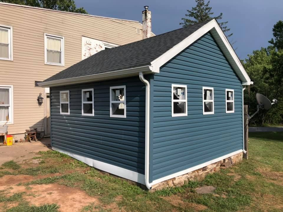 a blue garage with white trim and windows is next to a house