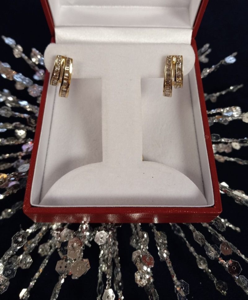 A pair of gold hoop earrings in a red box