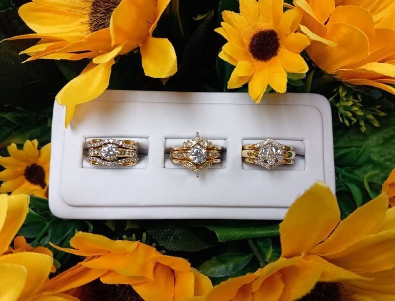 Three rings are in a white box surrounded by yellow flowers