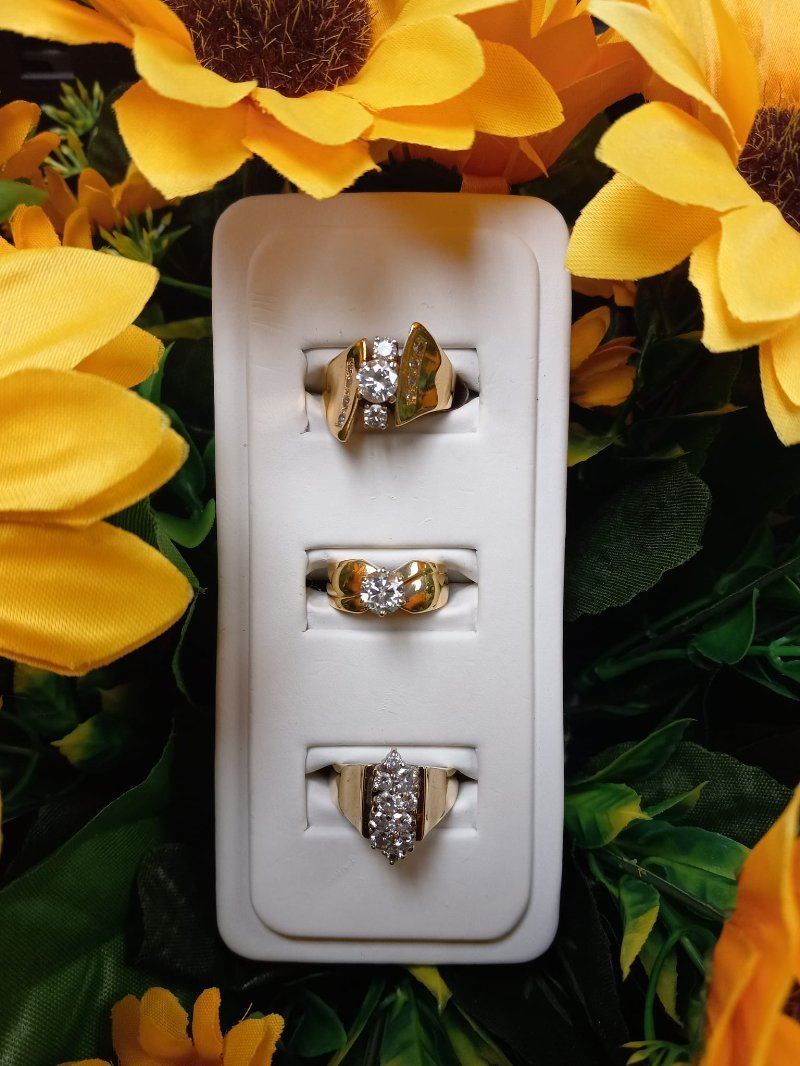 Three rings are sitting on a white display surrounded by sunflowers