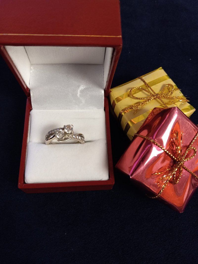 A ring in a red box next to two gift boxes